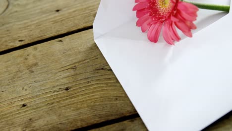 pink flower in envelope on wooden plank