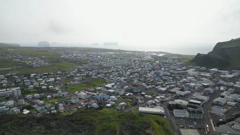nubes blanqueadas volando alrededor de una pequeña aldea construida en lava en el sur de islandia