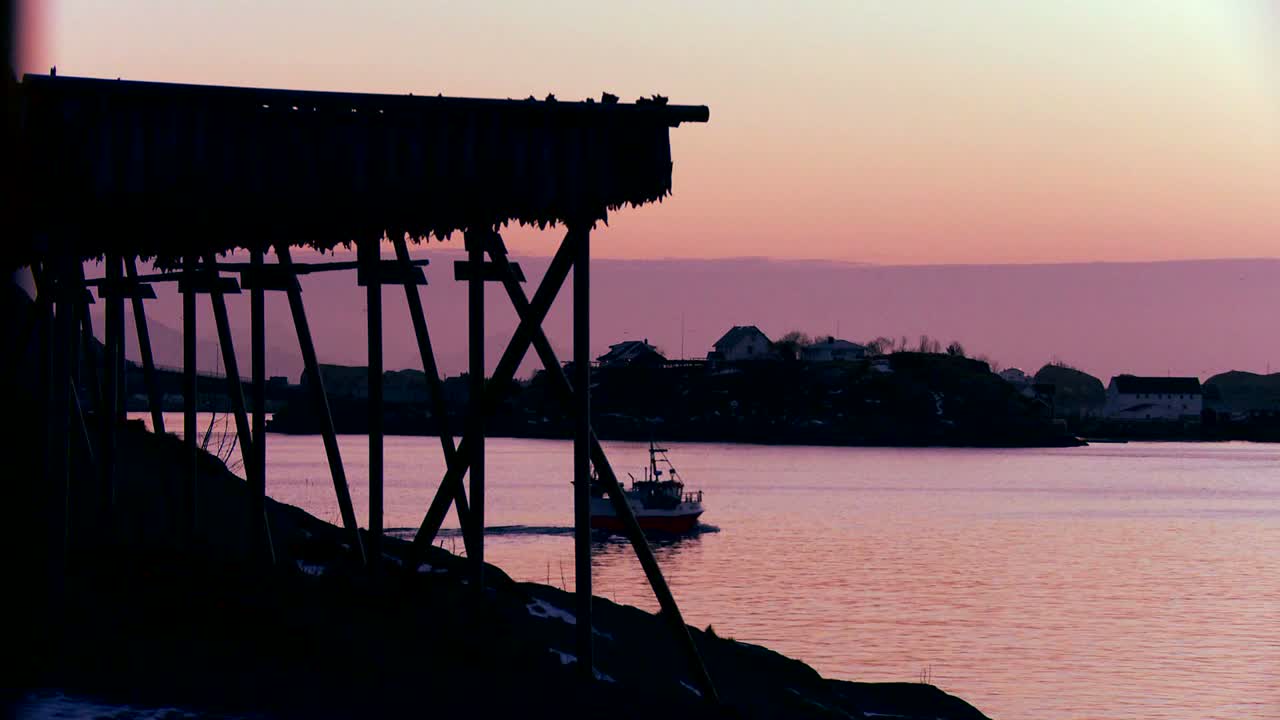 노르웨이 로포텐 섬의 석양에 어선이 북극의 피요르드를 통과합니다.