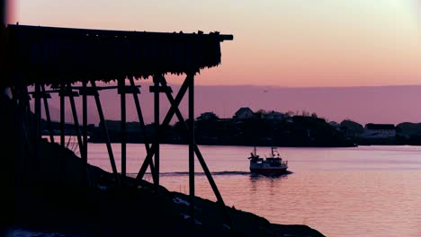 A-fishing-boat-heads-through-fjords-in-the-Arctic-at-sunset-in-the-Lofoten-Islands-Norway