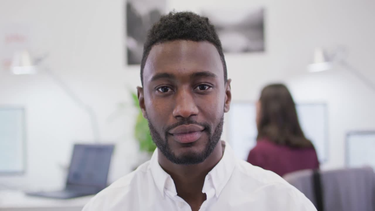 retrato de un empresario afroamericano sonriente mirando a la cámara en una oficina moderna