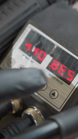 vista de cerca de una mano con guante ajustando el control de temperatura digital en una estación de soldadura, cambiando la temperatura de 242 grados a 238 grados