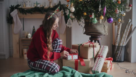 Hermosa-Mujer-Feliz-Arreglando-Regalos-Junto-Al-árbol-De-Navidad-En-Casa