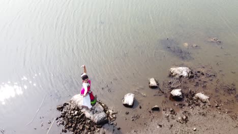 A-bharatnatyam-dancer-displaying-a-classical-bharatnatyam-pose-in-the-nature-of-Vadatalav-lake,-Pavagadh