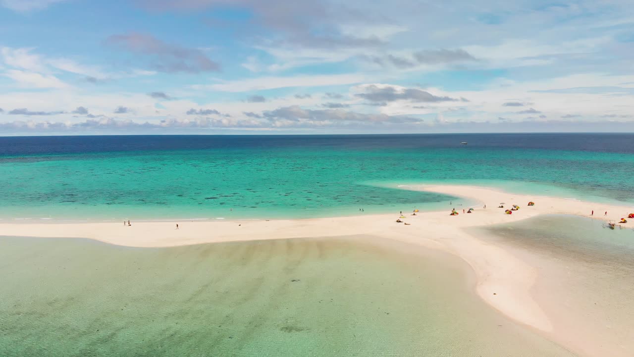 푸른 청록색 태평양과 푸른 하늘과 구름 드론 공중 4k로 둘러싸인 열대 백사장에서 편안한 휴가를 즐기는 관광객