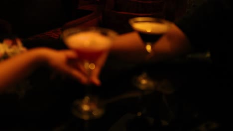 two people clinking glasses in dim lighting