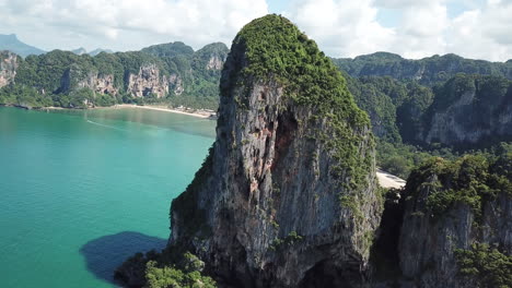 drone aerial view of limestone cliffs over turquoise sea water and white sand beach of tropical island, krabi thailand