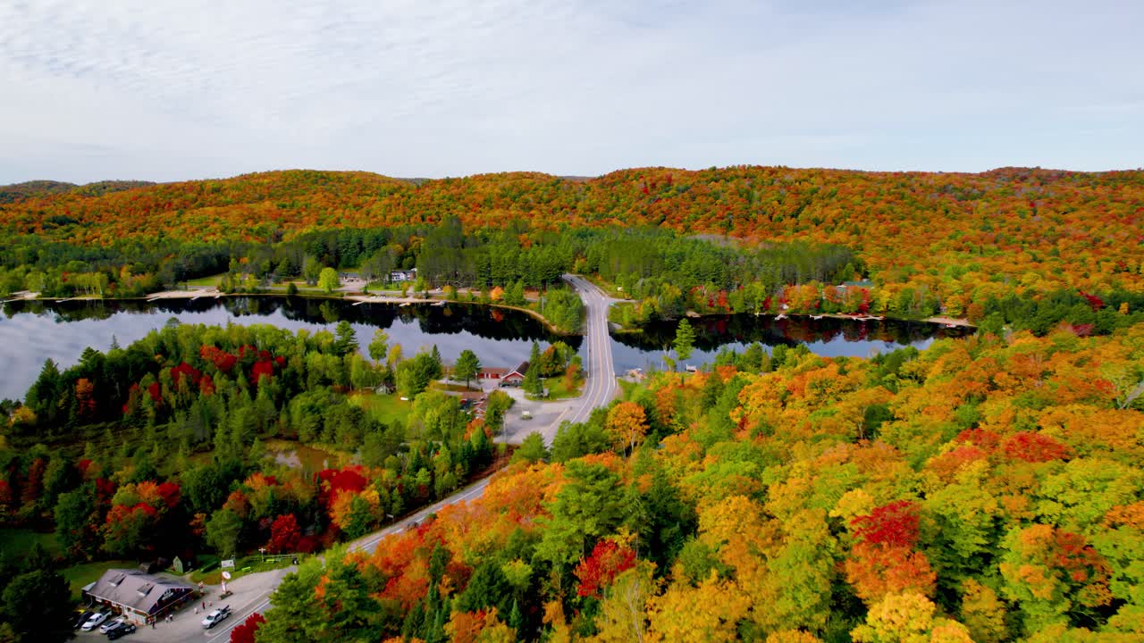 경치 좋은 가을 도로 여행 위에서 아래로 굴러가는 언덕을 통해 공중 전망 작은 마을 다채로운 나무와 호수를 가로지르는 다리