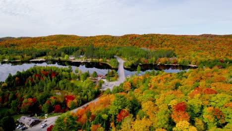 scenic fall road trip top down aerial view through rolling hills small town colorful trees and bridge across a lake