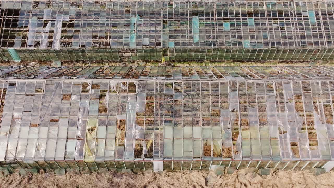 Top view of decaying greenhouse structures with camera slowly gliding backward