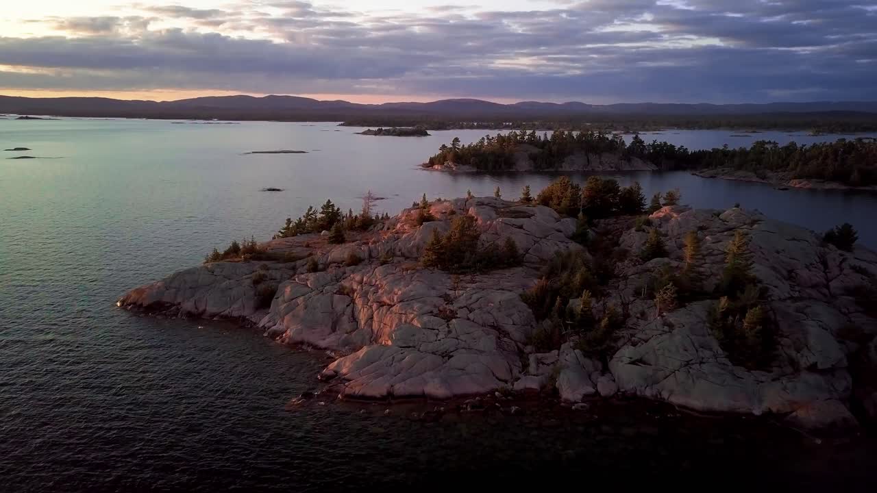 pequeña tienda de campaña blanca en una isla rocosa en el lago azul, plataforma rodante aérea de drones, inclinada hacia arriba