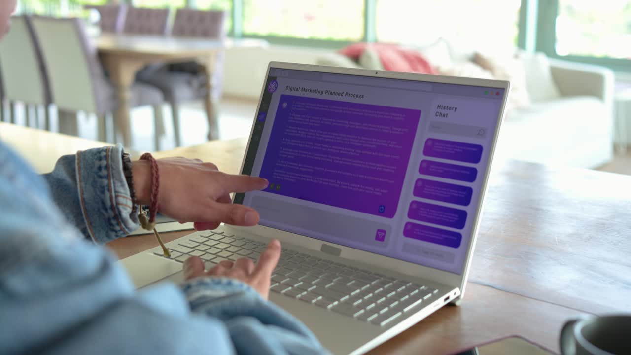 Woman sitting at table with laptop in office typing query, scrolling marketing plan and reflecting