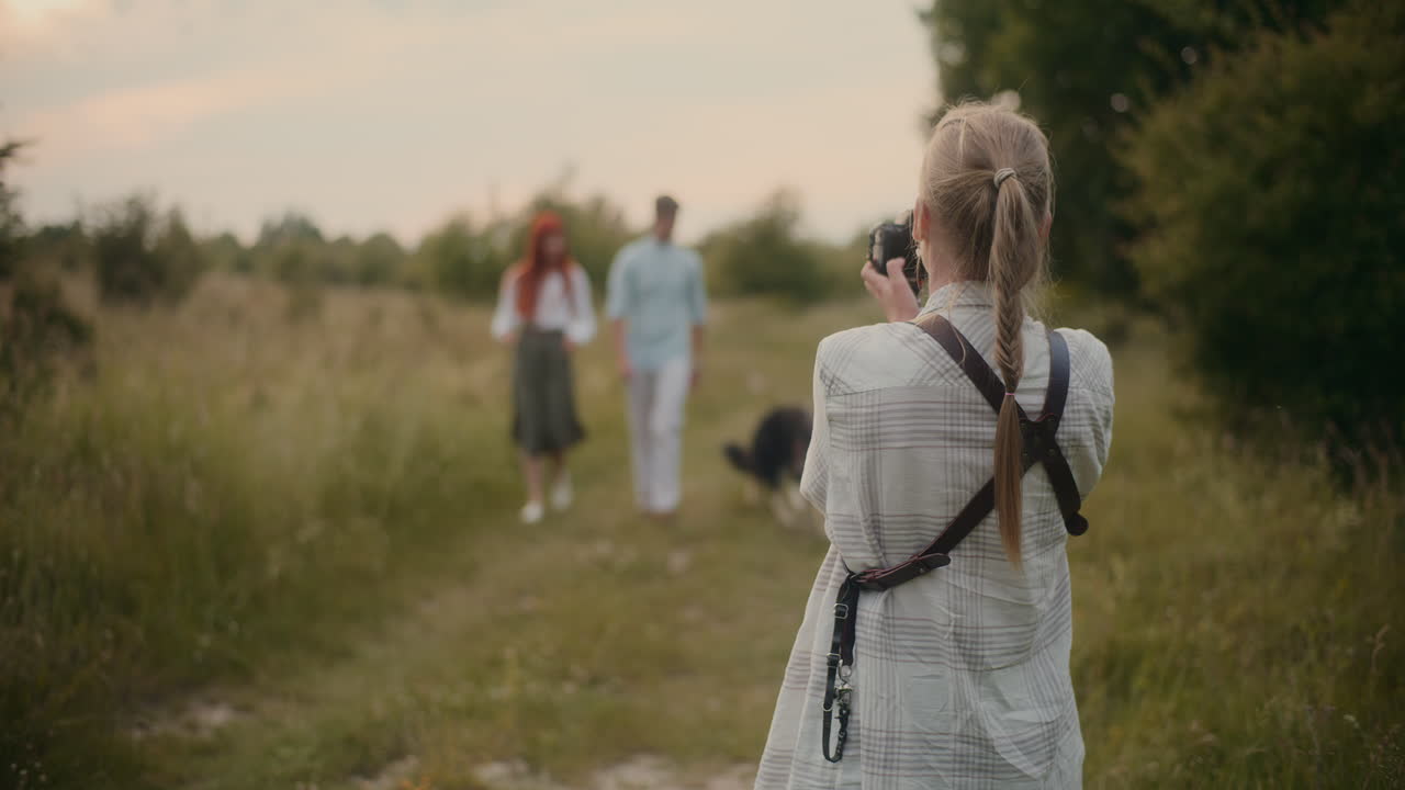 Woman taking a photo of people in a field
