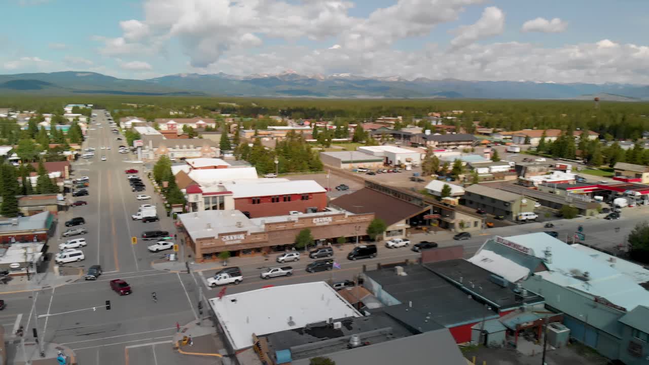 pan vista sobre el centro de la ciudad de west yellowstone con la avenida y las montañas en el horizonte, montana, ee.