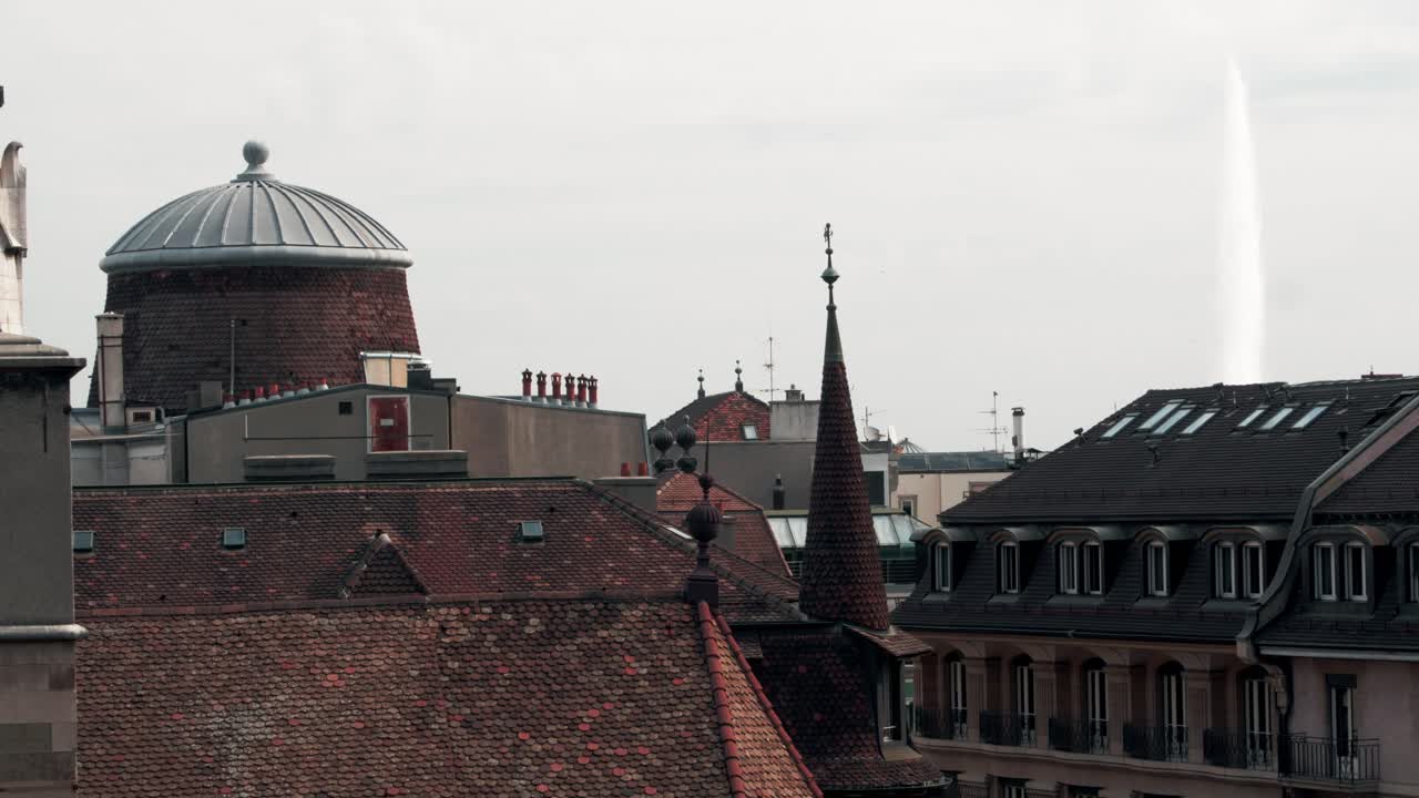 Prospettiva dai tetti nel centro di Ginevra che mostra tetti in tegole rosse, una classica struttura a cupola e una guglia appuntita. Ripresa dall'alto.