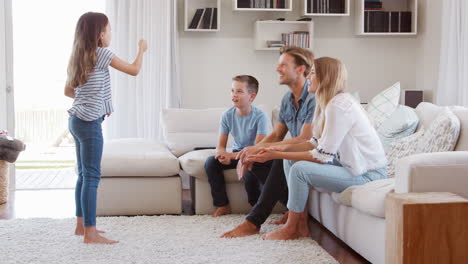 family sitting on sofa at home playing charades