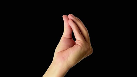 close up shot of a male hand throwing an italian-style perfect sign, against a plain black background