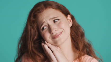 redheaded girl in front of camera on turquoise background.