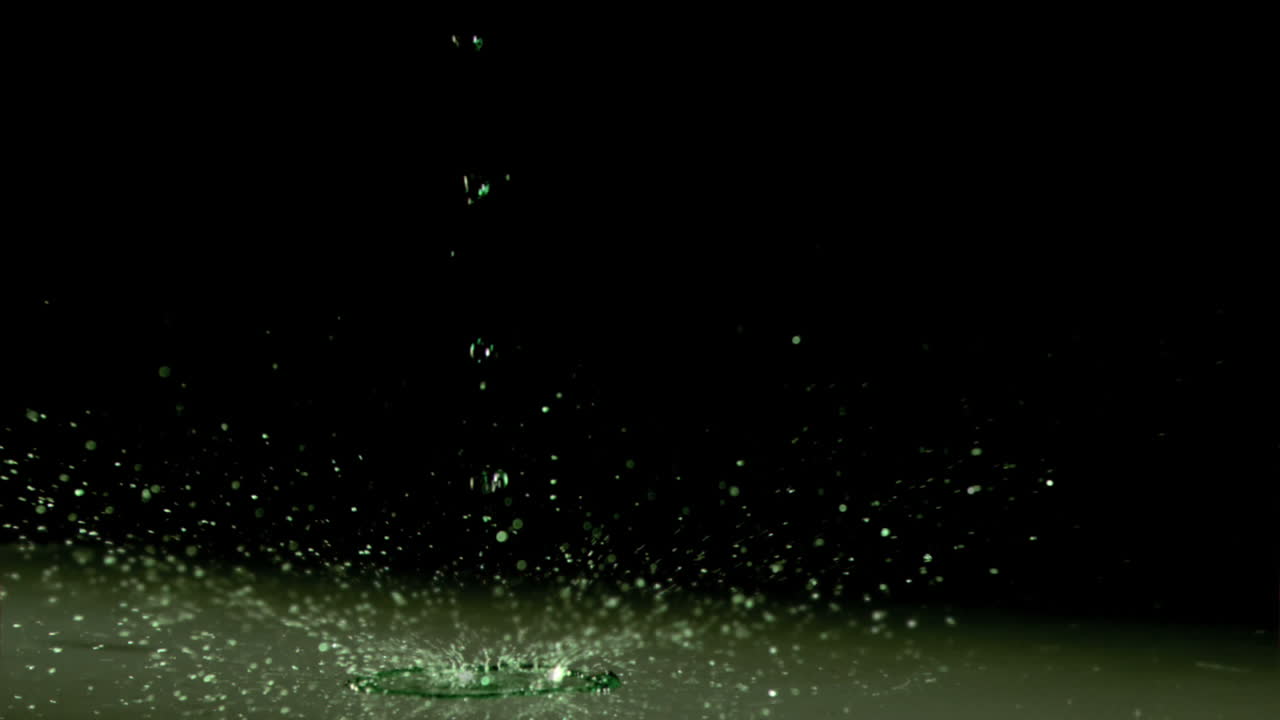 녹색 빛 아래에서 초 느린 동작으로 액체가 흘러내립니다.