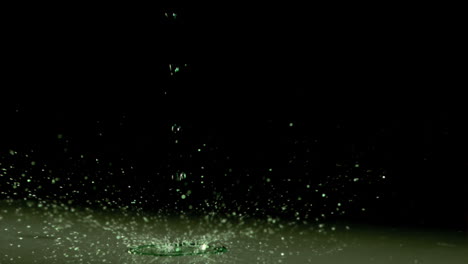 liquid dripping in super slow motion under green light