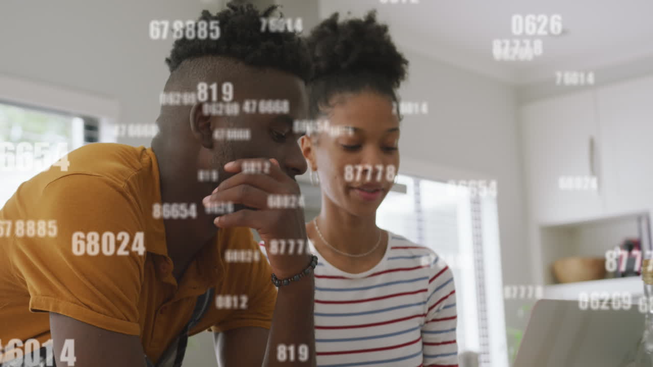 animación de números cambiantes sobre una pareja diversa viendo videos en una computadora portátil en la cocina