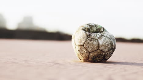 vieja pelota de fútbol desinflada en una playa de arena