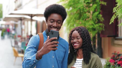 african american man and woman making a selfie with smartphone in the street