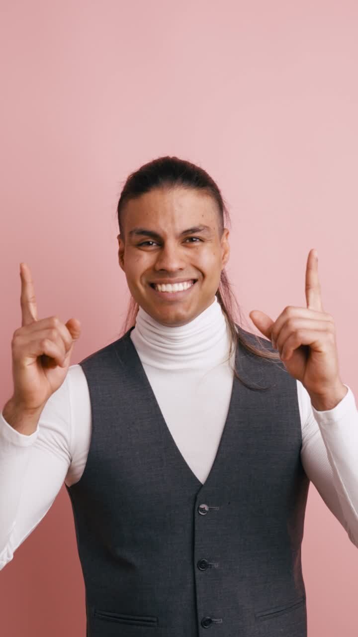 Happy Man Pointing Upwards with Both Hands and Smiling
