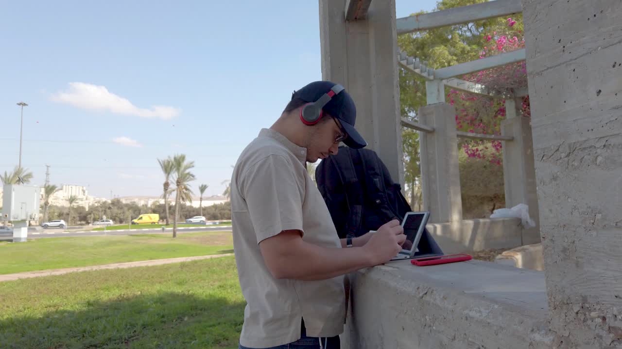Young man using his tablet in a park on a sunny day.