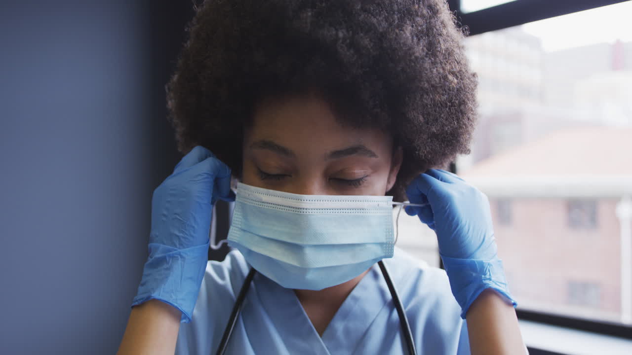 Medico donna birazziale che si toglie una mascherina, guarda la telecamera e sorride