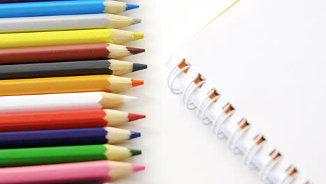 lápices de colores con libro en espiral