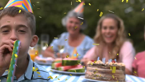 boy blowing party horn with confetti animation over family gathering outdoors