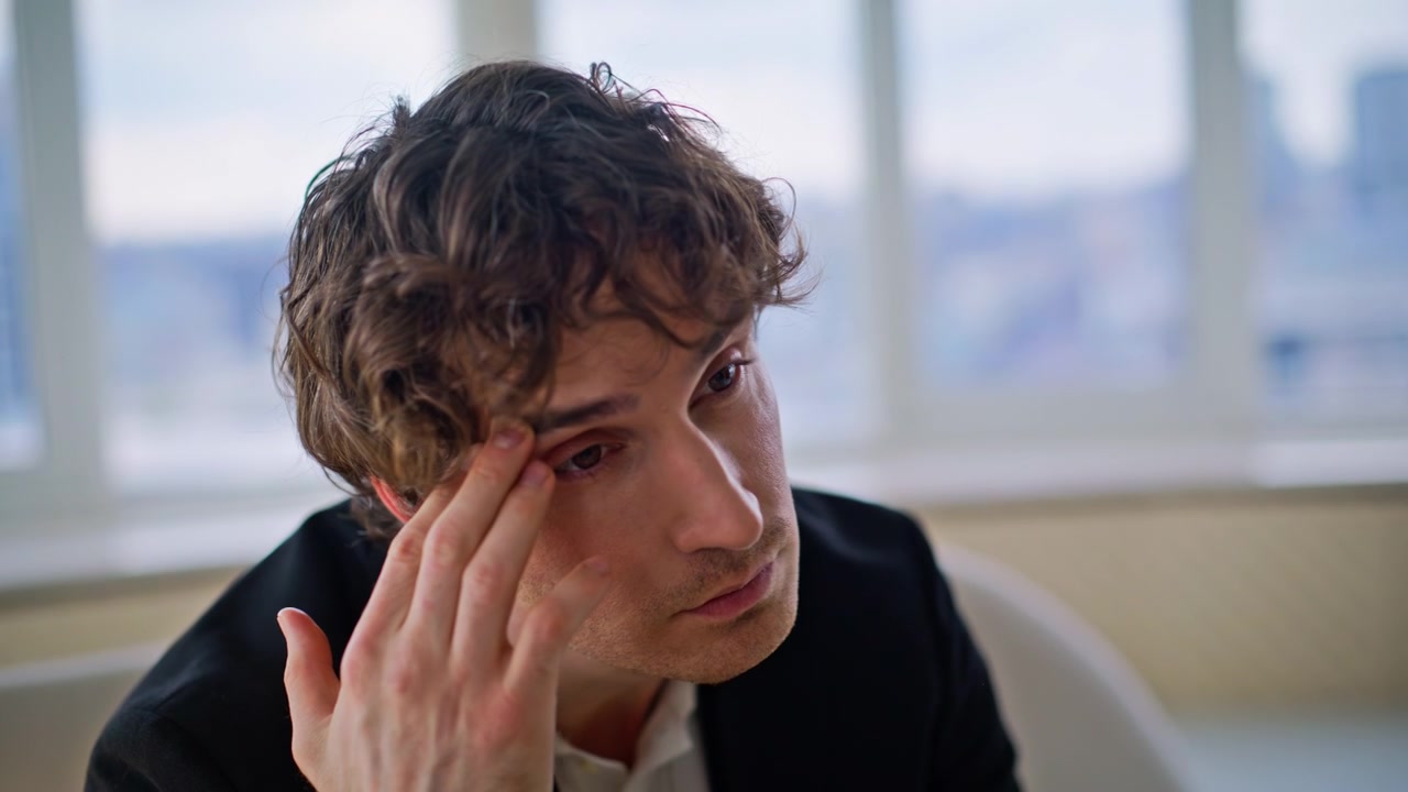 Exhausted man rubbing eyes office. Pensive businessman thinking window view.
