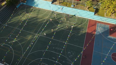 slow motion drone shot of children playing football on soccer court of buenos aires at sunset