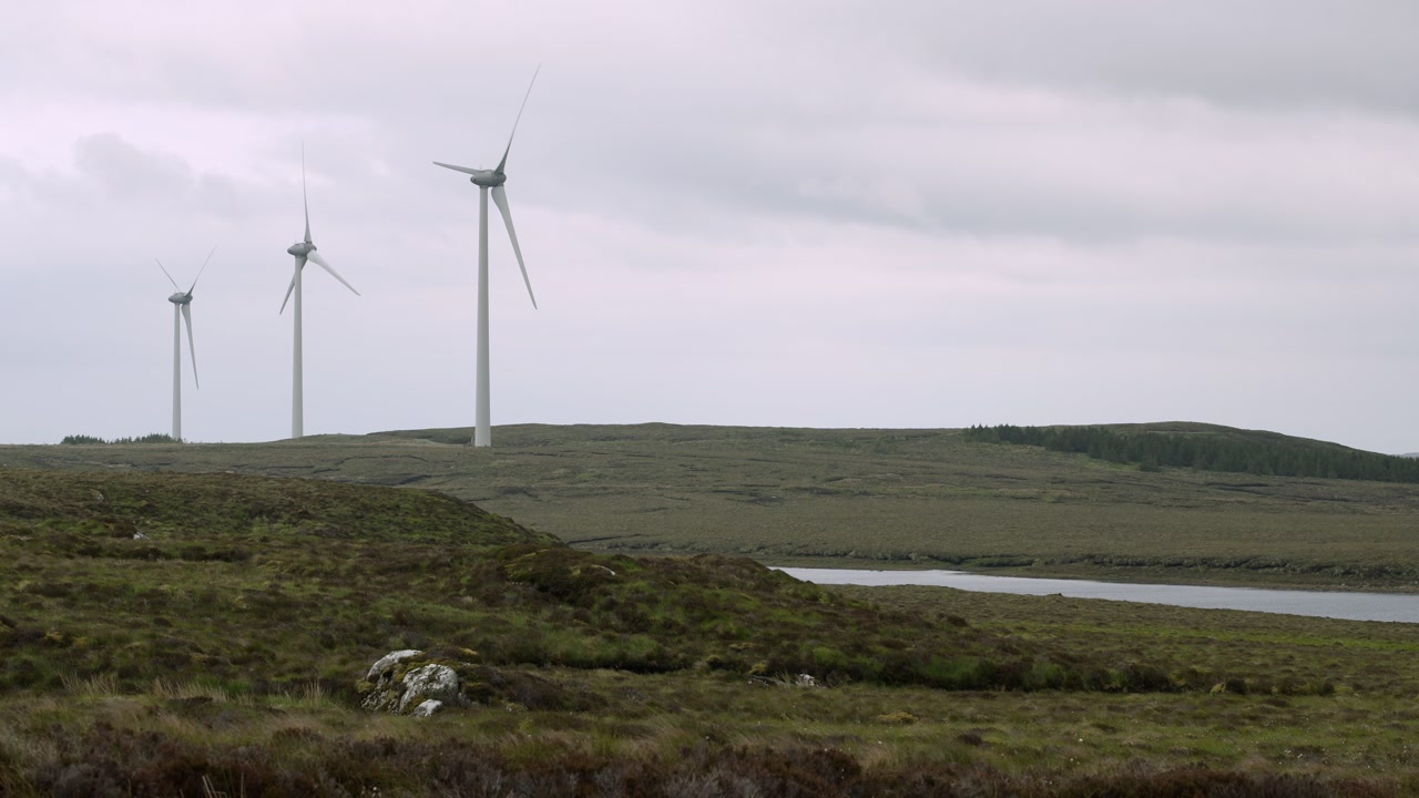 Static shot of an active wind farm by a loch on a Hebridean moorland.
