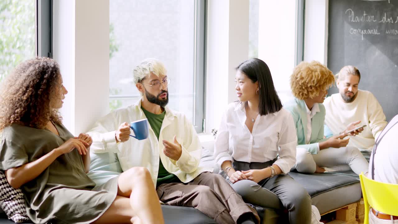 Coworkers chatting relaxed during coffee break sitting on comfortable chairs