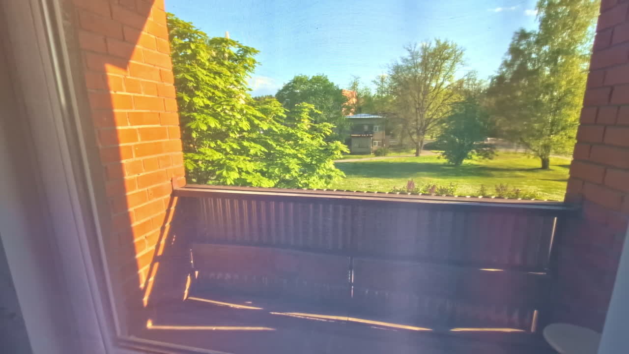Sunlight Illuminating Apartment Balcony With View of Park and Trees Outside