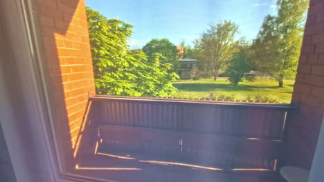 sunlight illuminating apartment balcony with view of park and trees outside