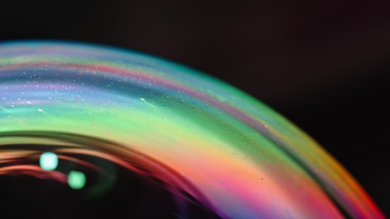 Colorful bubble close-up with smooth curved rainbow-like iridescence and blurred background