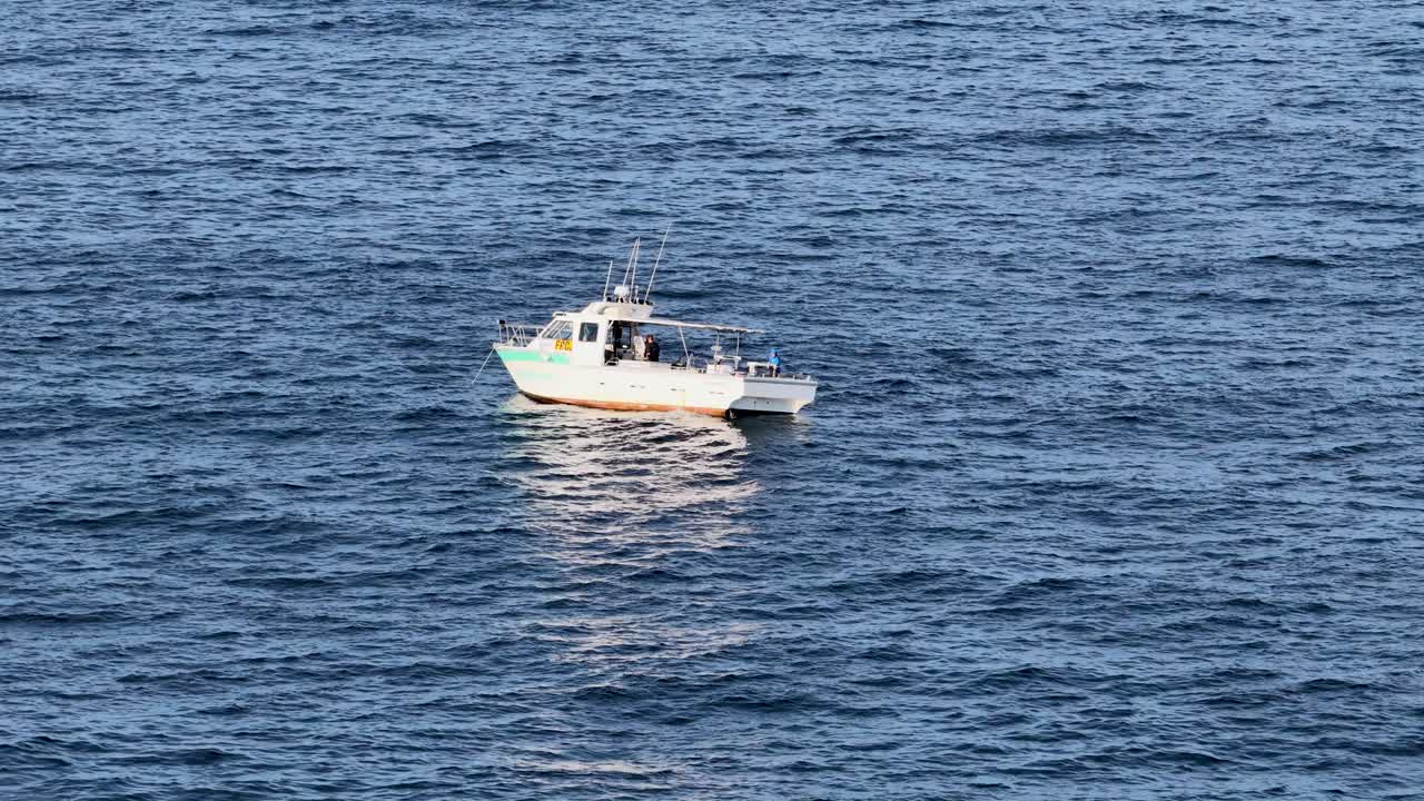 A drone captures a fishing boat cruising alone on deep blue ocean near Gold Coast, Australia, under natural daylight with gentle camera movement