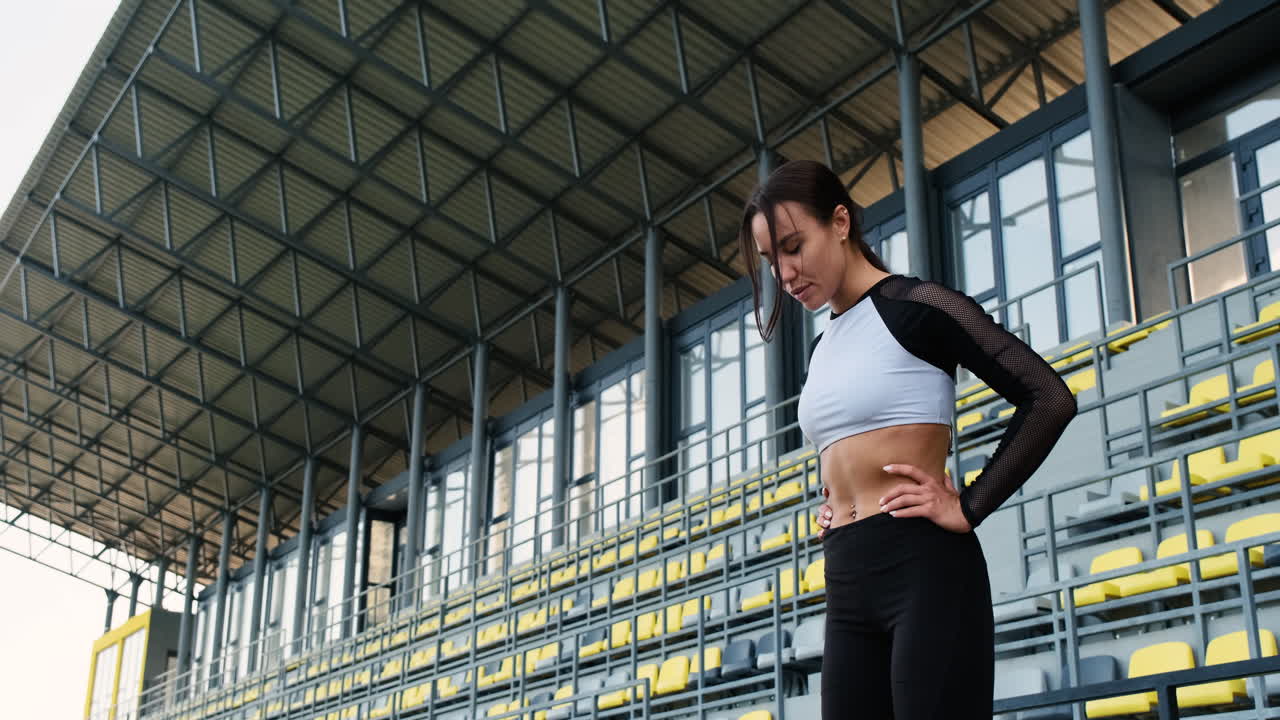 bella mujer deportiva concentrándose antes de hacer ejercicio al aire libre en el estadio