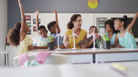 video de una feliz maestra caucásica y una clase de alumnos diversos estudiando ecología en el aula