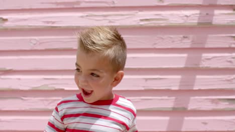 portrait of happy caucasian boy cheering and raising hands over beach house