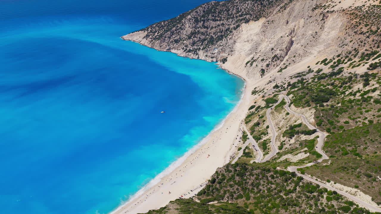 Myrtos beach turquoise blue waters with limestone cliffs, steep and narrow hairpin turn roads, Kefalonia island, Ionian Sea, Panoramic view, Drone shot