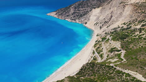 myrtos beach turquoise blue waters with limestone cliffs, steep and narrow hairpin turn roads, kefalonia island, ionian sea, panoramic view, drone shot