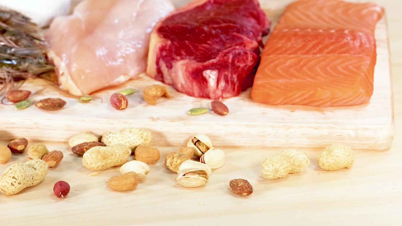 고기, 생선, 견과류 등 단백질이 풍부한 다양한 음식들이 나무판 위에 끔하게 배열되어 있습니다.