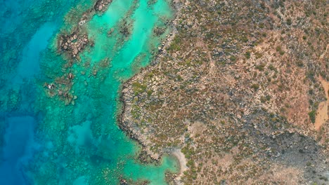 Vista-De-Arriba-Hacia-Abajo-Agua-Turquesa-Cristalina-Con-Costa-Rocosa,-Isla-De-Creta