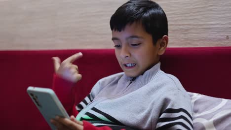 young kid watching mobile and playing online game at home at night from different perspective
