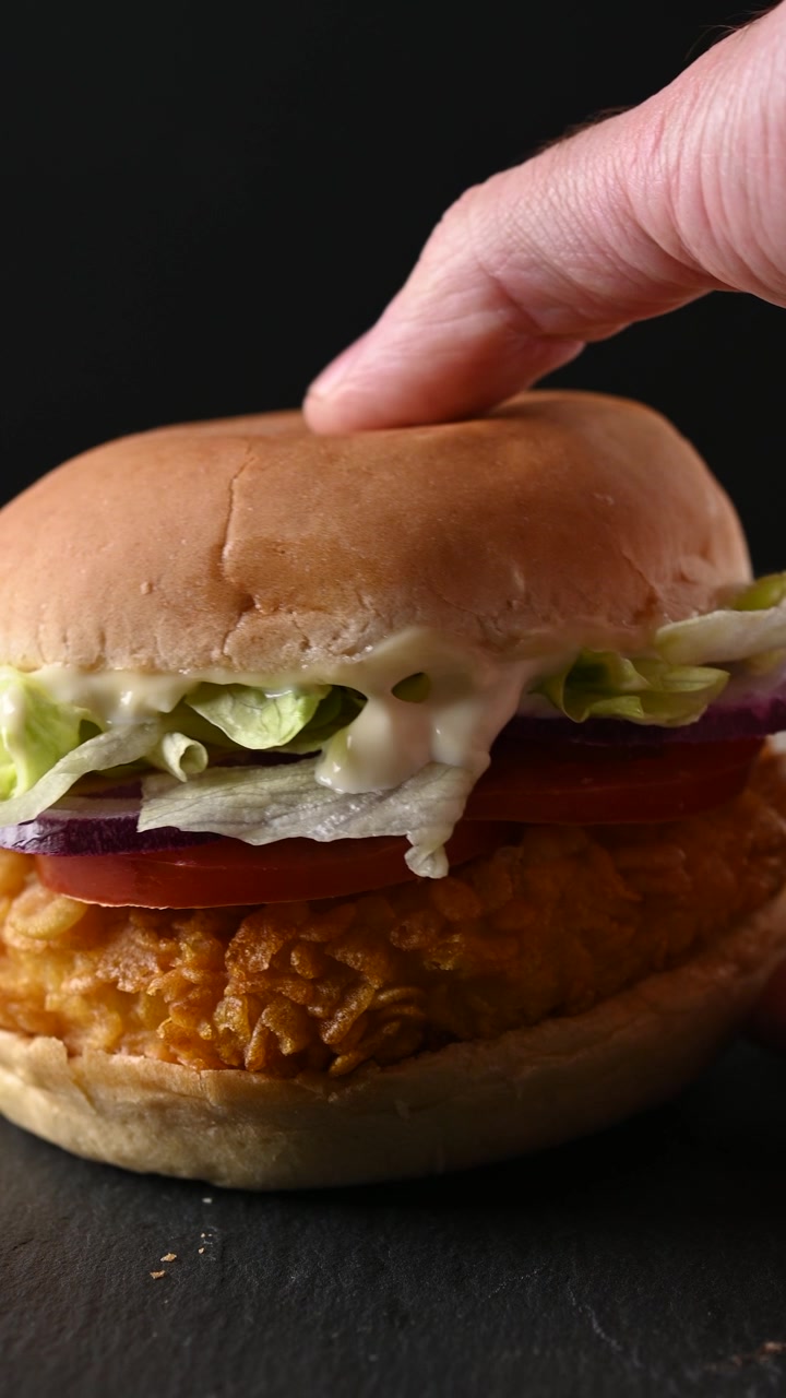 Mano che prende un hamburger di pollo croccante
