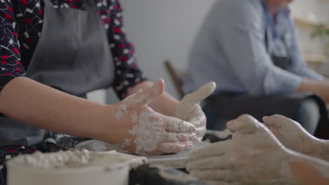 la mujer maestra transfiere el conocimiento a una mujer mayor que trabaja en una rueda de alfarero y hace una taza de cerámica en su taller en cámara lenta